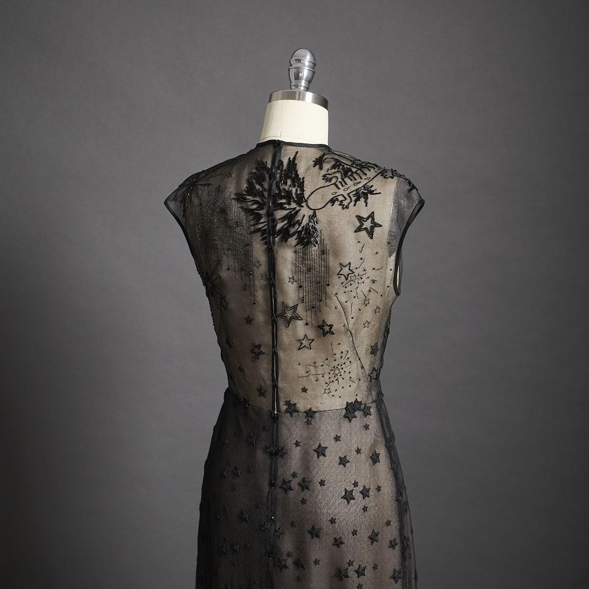 A black A-line gown featuring hand-embroidered stars out of metallic thread and adorned with Swarovski crystals on soft tulle. - DELPHINE GENIN